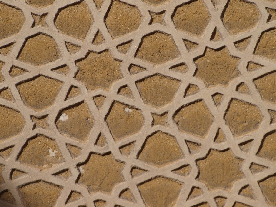 Patrón geométrico en relieve con formas de estrellas sobre fondo marrón.